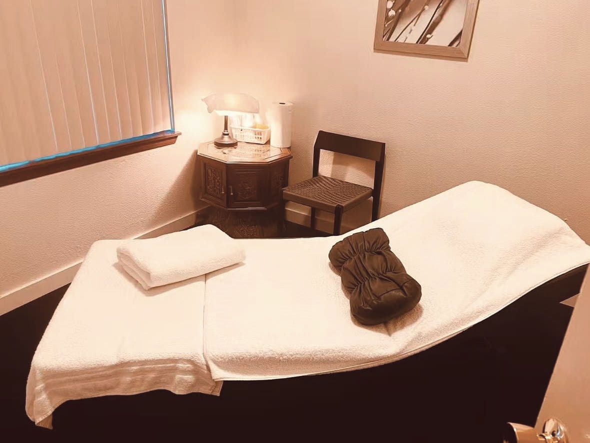 Single massage table with folded towels and a lamp turned low at Green Lake Spa