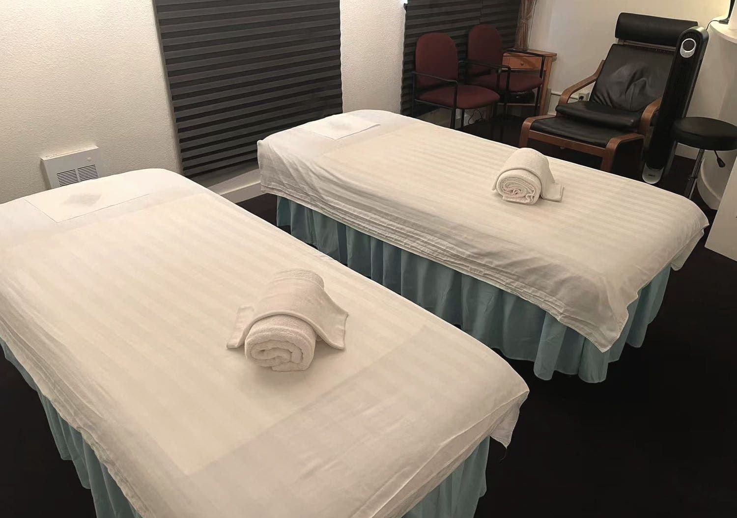 Two massage tables side by side, dressed in fresh linen with rolled towels, at Green Lake Spa in Seattle